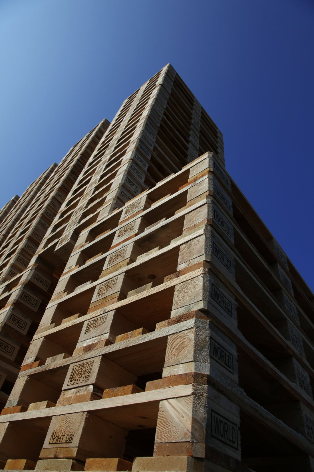 Turm gestapelter Europaletten vor blauem Himmel